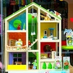 A vibrant dollhouse and stuffed toys displayed in a toy store window, perfect for children's play.